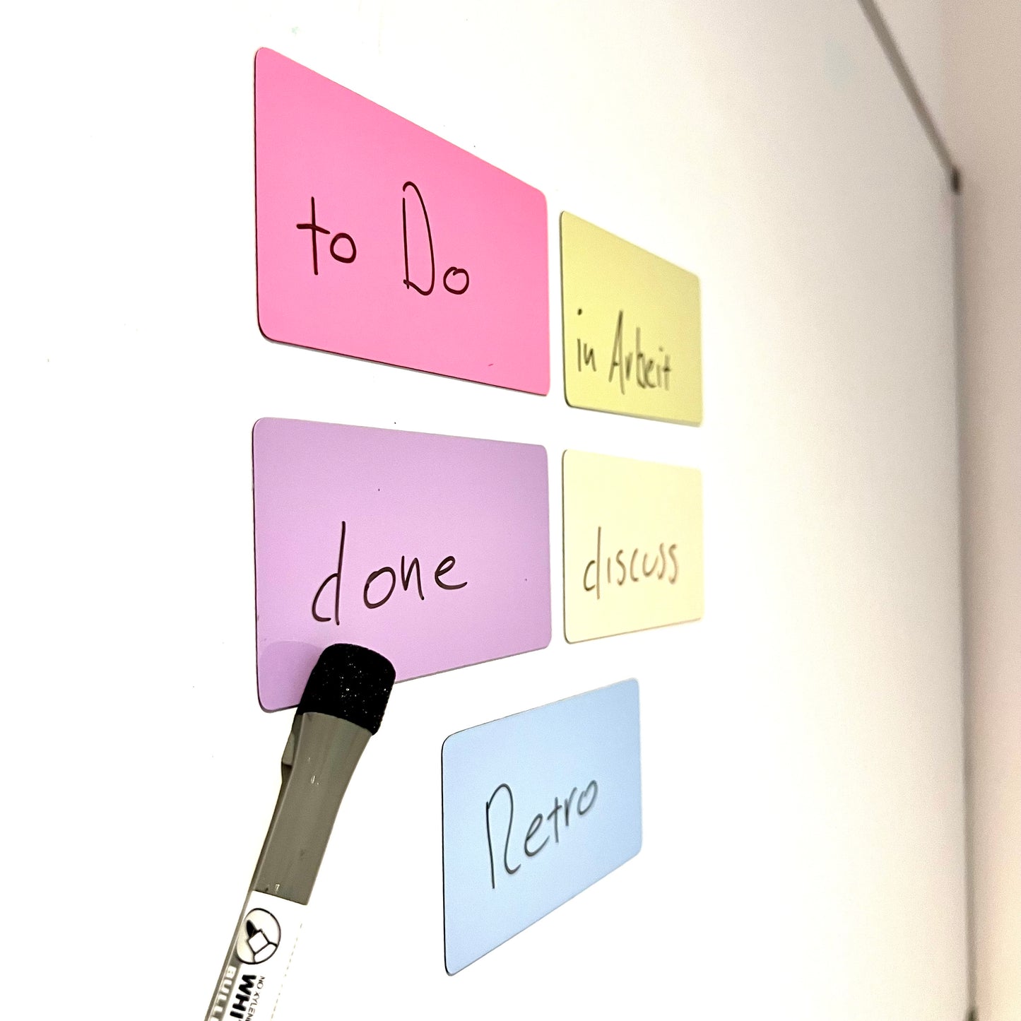 Magnetische Moderationskarten in verschiedenen Farben mit handgeschriebenen Begriffen an einer Wand.