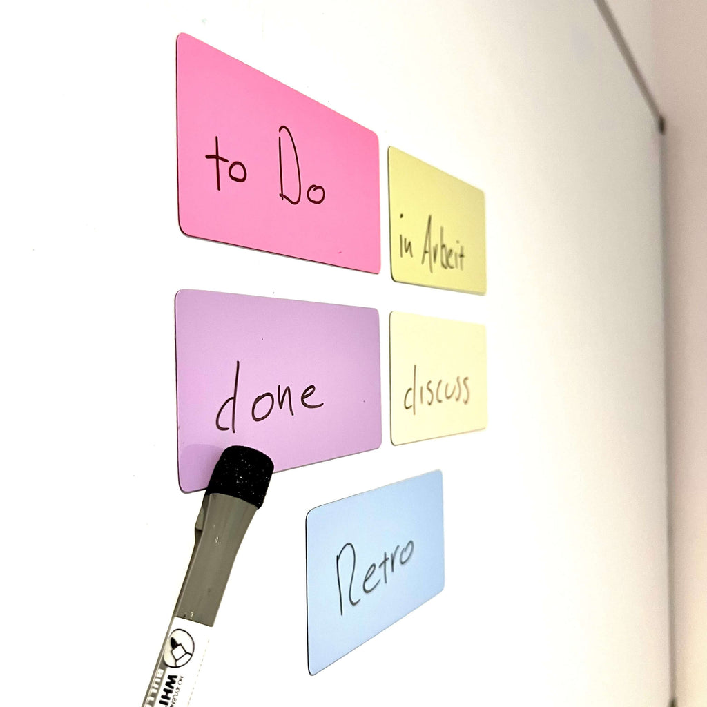 Magnetische Moderationskarten in verschiedenen Farben mit handgeschriebenen Begriffen an einer Wand.
